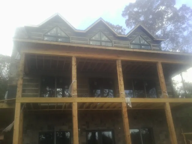 Dormers and porch framing on a large log home under construction — Roof Coating work by our crew in Milledgeville