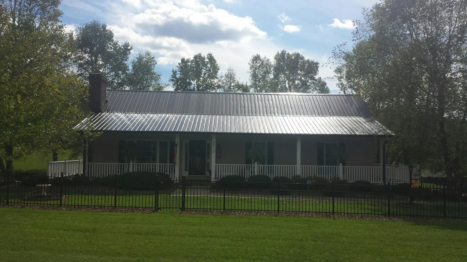 Gray metal roof on a brick ranch with a full width front porch — Gutter Guard Installation work by our crew in Milledgeville