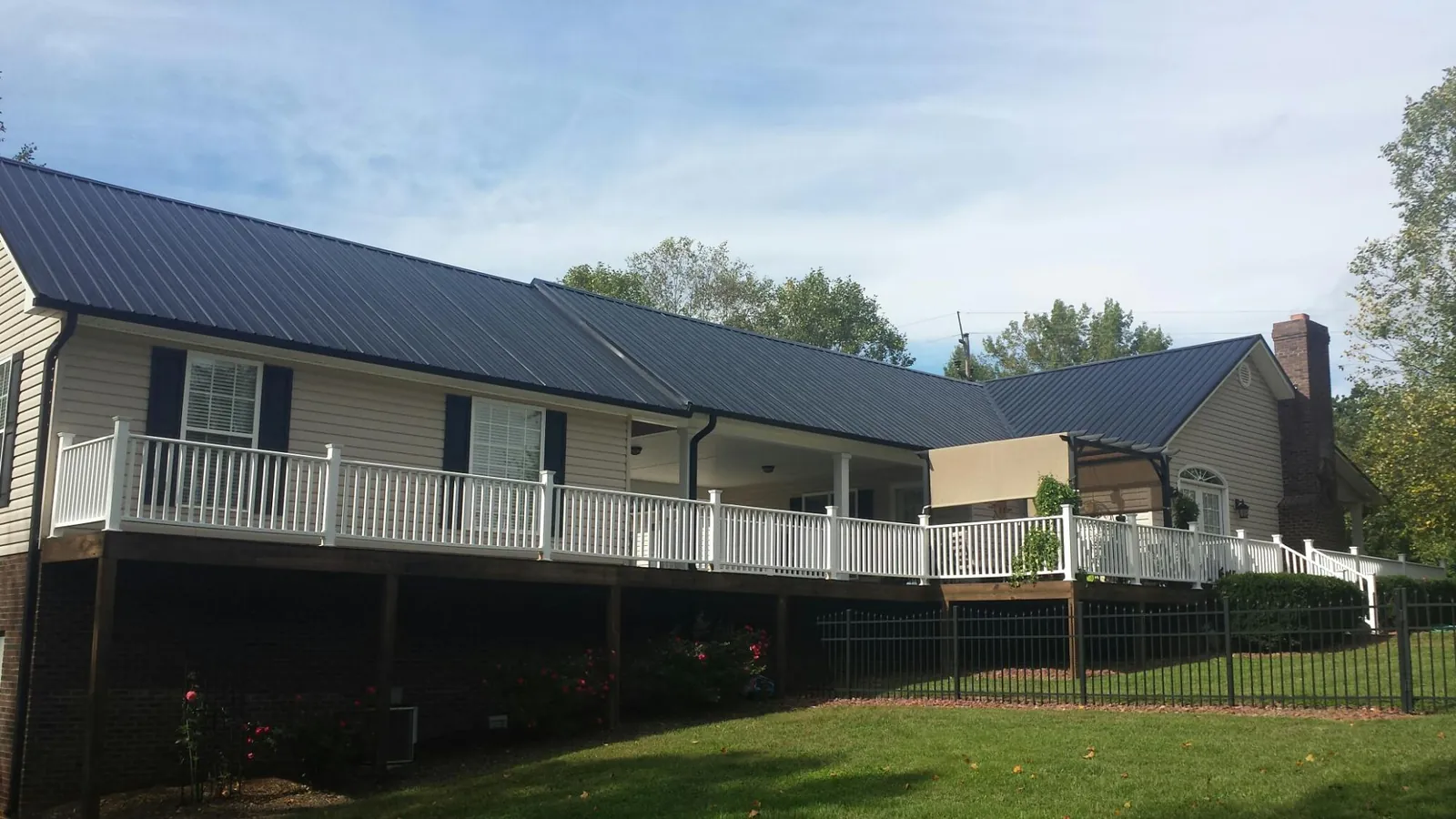 Black metal roof above a long white railed deck on a hillside home in Milledgeville